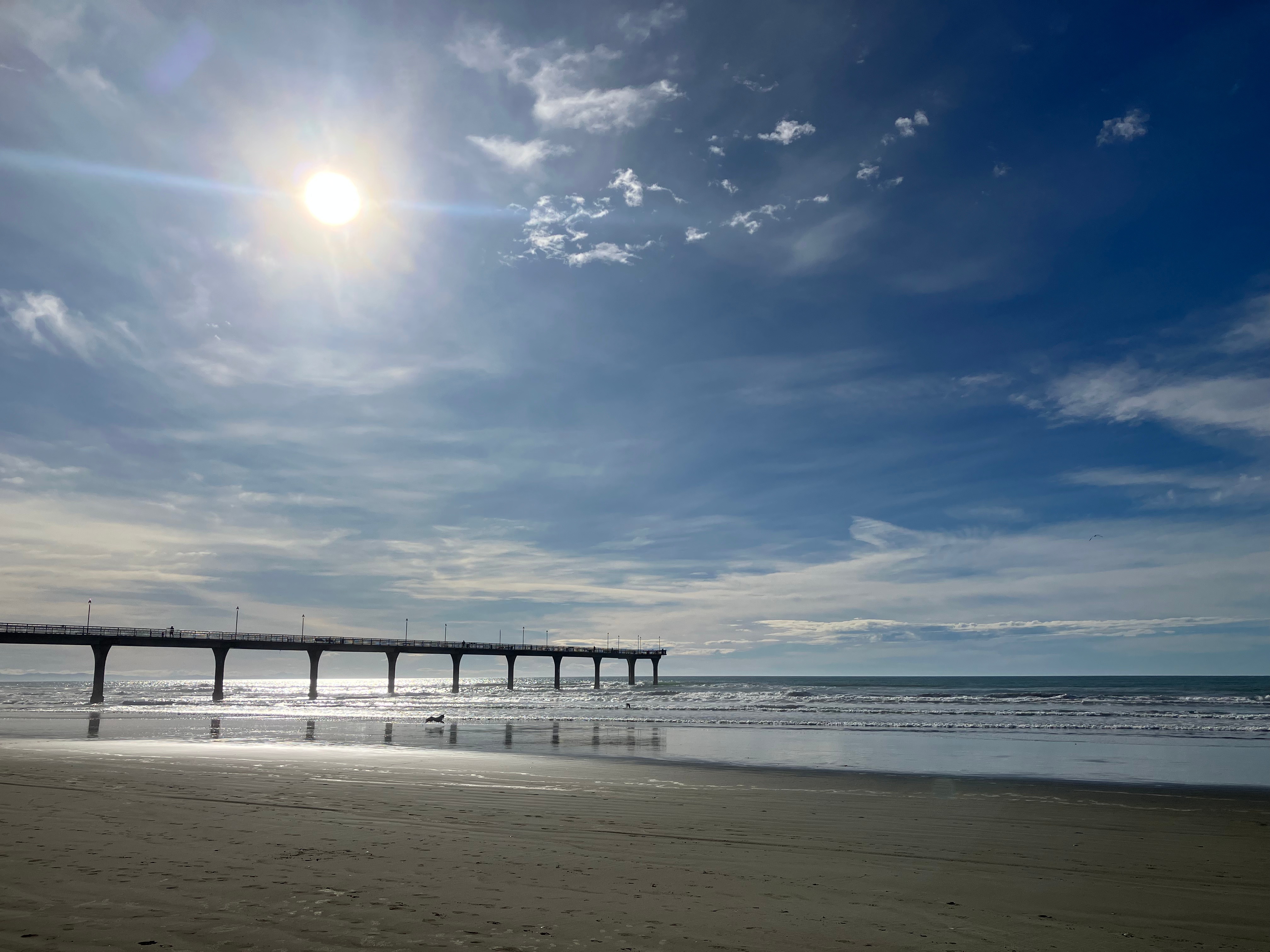 Photo taken from south of New Brighton pier, showing it backlit with the sun above it, denoting bridges between different states, and energy. Credit: aimee whitcroft, 2026.